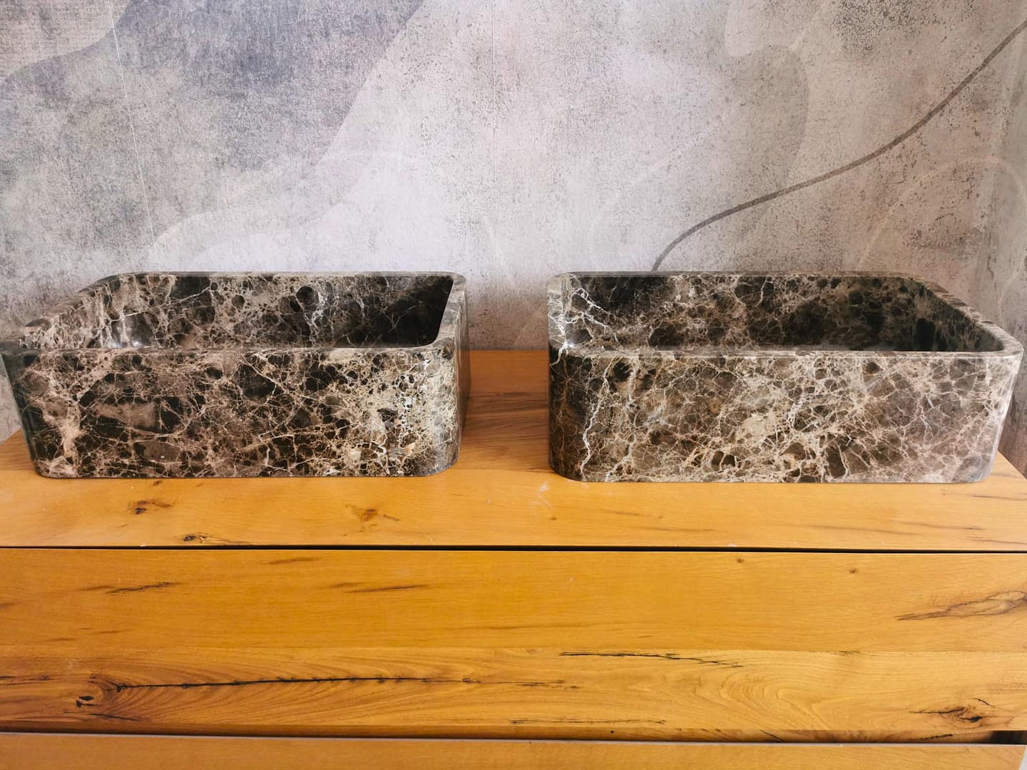Due lavabi in marmo Emperador Dark, con tonalità calde e venature chiare distribuite sulla superficie.