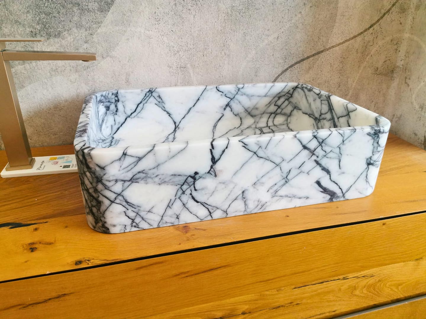 Vista frontale di un lavabo Lilac da appoggio, con venature grigio-nere in forte contrasto sul marmo bianco.
