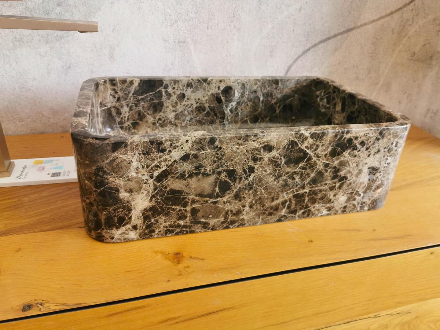 Vista laterale di un lavabo Emperador Dark, con angoli stondati e trama beige su fondo marrone scuro.